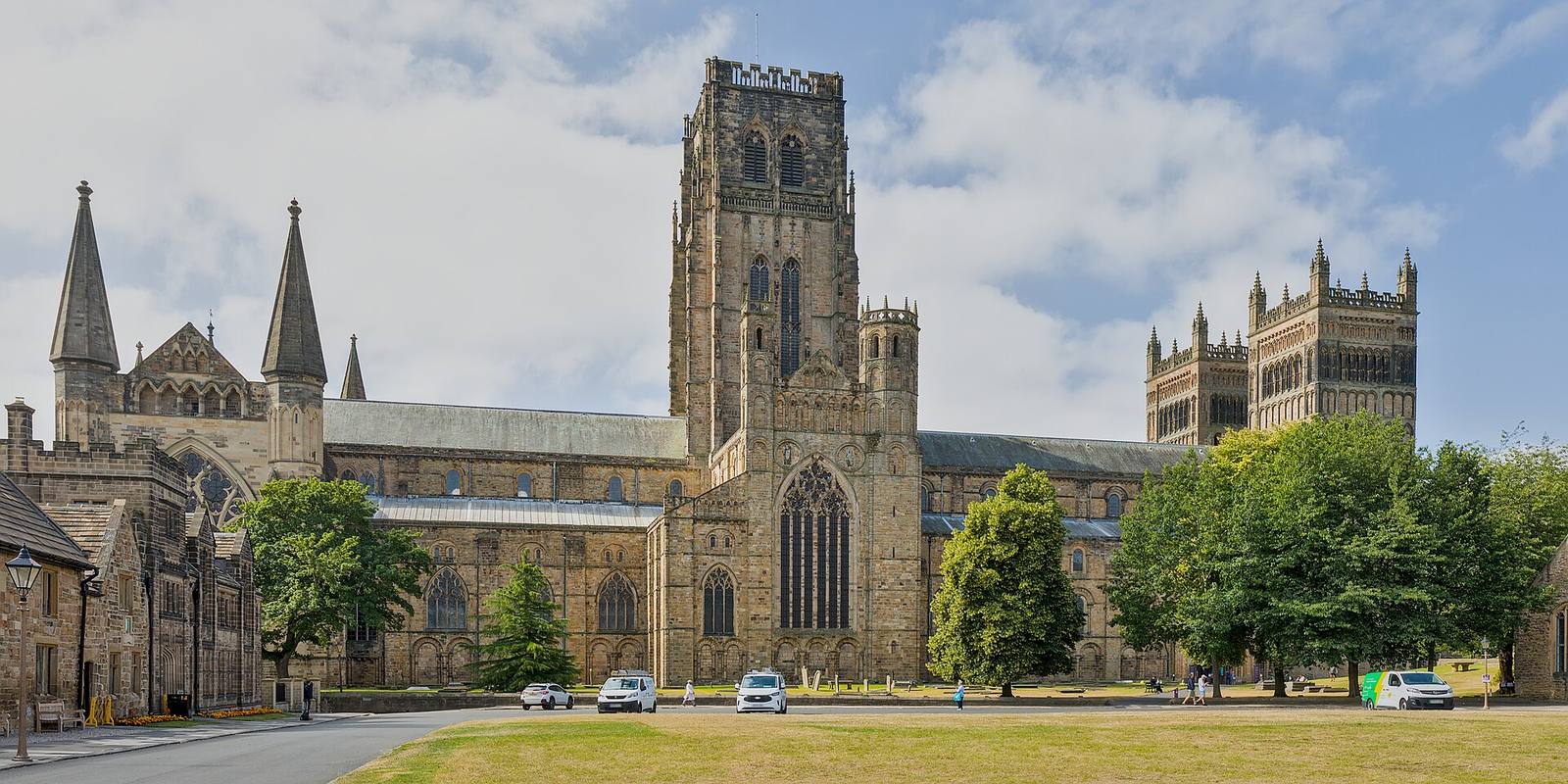 Durham Cathedral’s long nave and massive central tower seen from the north, with trees in front.