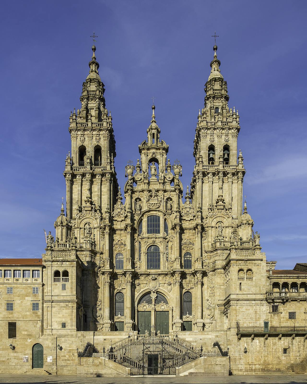 The Baroque west front of Santiago de Compostela Cathedral, with its two tall towers, under a blue sky.