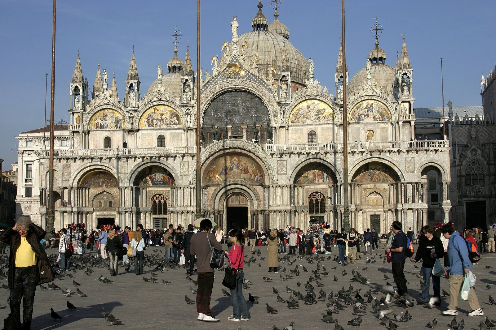 The domes and mosaic-filled arches of St Mark’s Basilica, with visitors in the square.